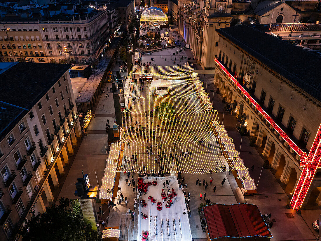 Luftaufnahme der nächtlich beleuchteten Weihnachtsdekoration und -unterhaltung auf dem El Pilar-Platz in Zaragoza, Spanien