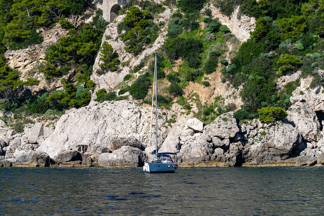 A sailboat anchored in the waters of the Tyrrhenian Sea off the coast of the island of Capri, Italy.