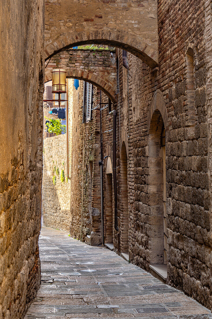 Eine mittelalterliche Architektur in einer engen Seitenstraße in der ummauerten Stadt San Gimignano, Italien.