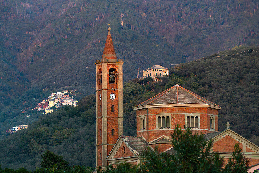 Die Kirche Nostra Signora della Guardia mit ihrem Glockenturm in Levanto, Italien. Dahinter liegt ein Dorf auf einem Hügel.