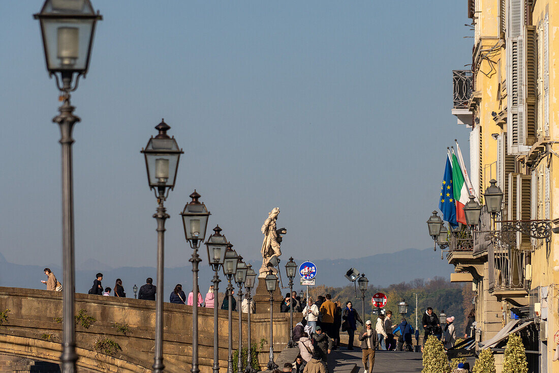 Tourists at the Ponte Santa Trinita or Holy Trinity Bridge across the Arno River in Florence, Italy.