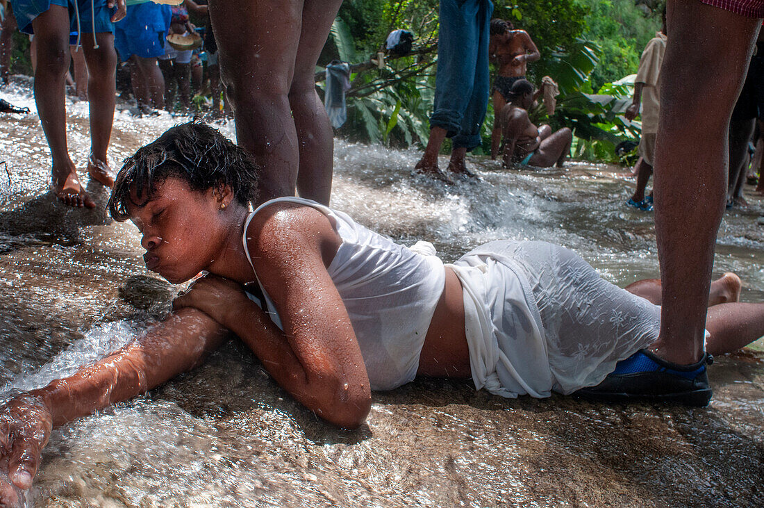 Haiti Voodoo Festival in Saut d'Eau, in Saut d'Eau, Ville Bonheur, Haiti. Tausende von Vodou- und katholischen Anhängern versammelten sich unter dem Wasserfall von Saut d'Eau in Haiti. Die Wallfahrt, die sowohl von Voodou-Anhängern als auch von Katholiken unternommen wird, hat ihren Ursprung in der Sichtung des Bildes der Jungfrau Maria auf einem Palmblatt in der Nähe des Wasserfalls vor einem halben Jahrhundert. Der Katholizismus und die Voodou-Praktiken sind in ihrer haitianischen Form für immer miteinander verwoben. Das Erscheinen eines Regenbogens unter den Wasserfällen soll bedeuten, dass