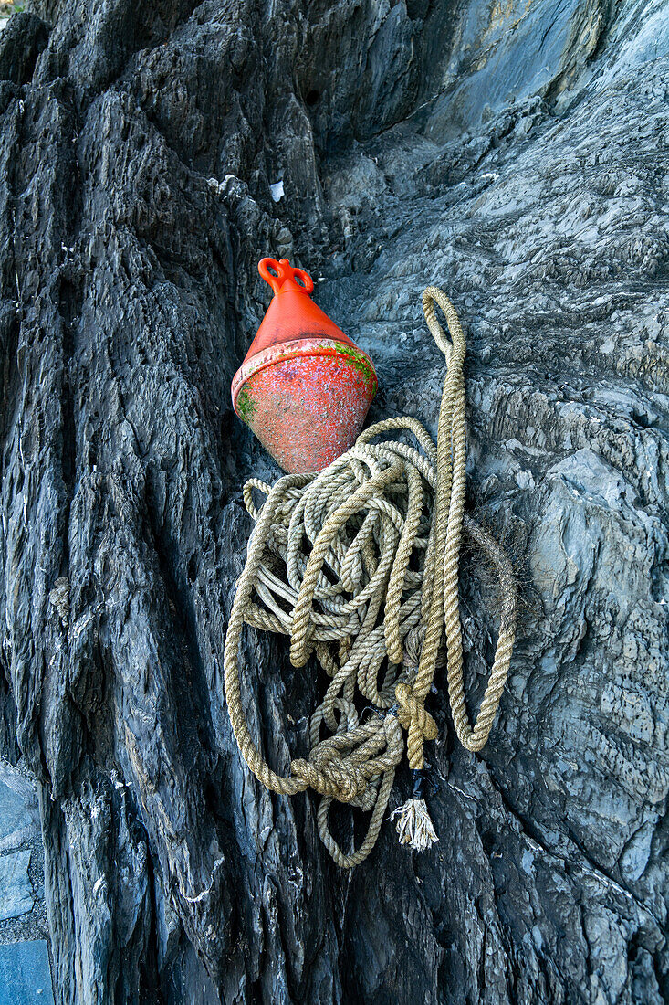 A mooring buoy and line in the rocks of the harbor of the fishing village of Manarola, Cinque Terre, Italy.