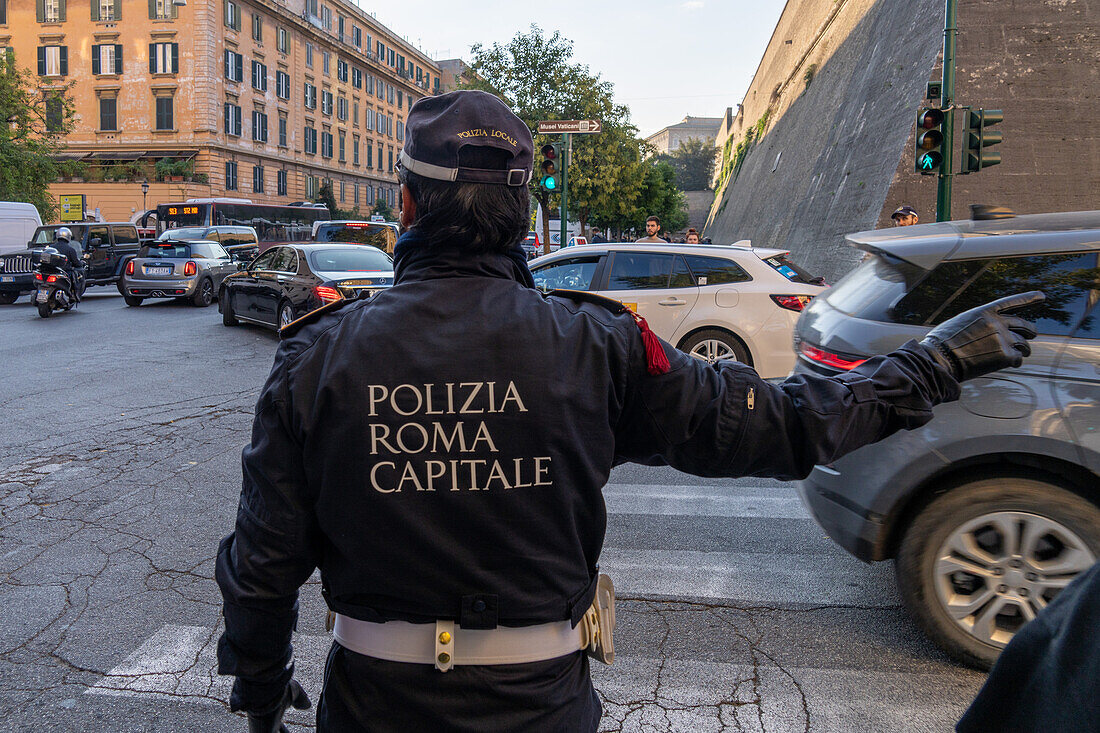 A policeman directs traffic on the street by the wall of the Vatican City in Rome, Italy.