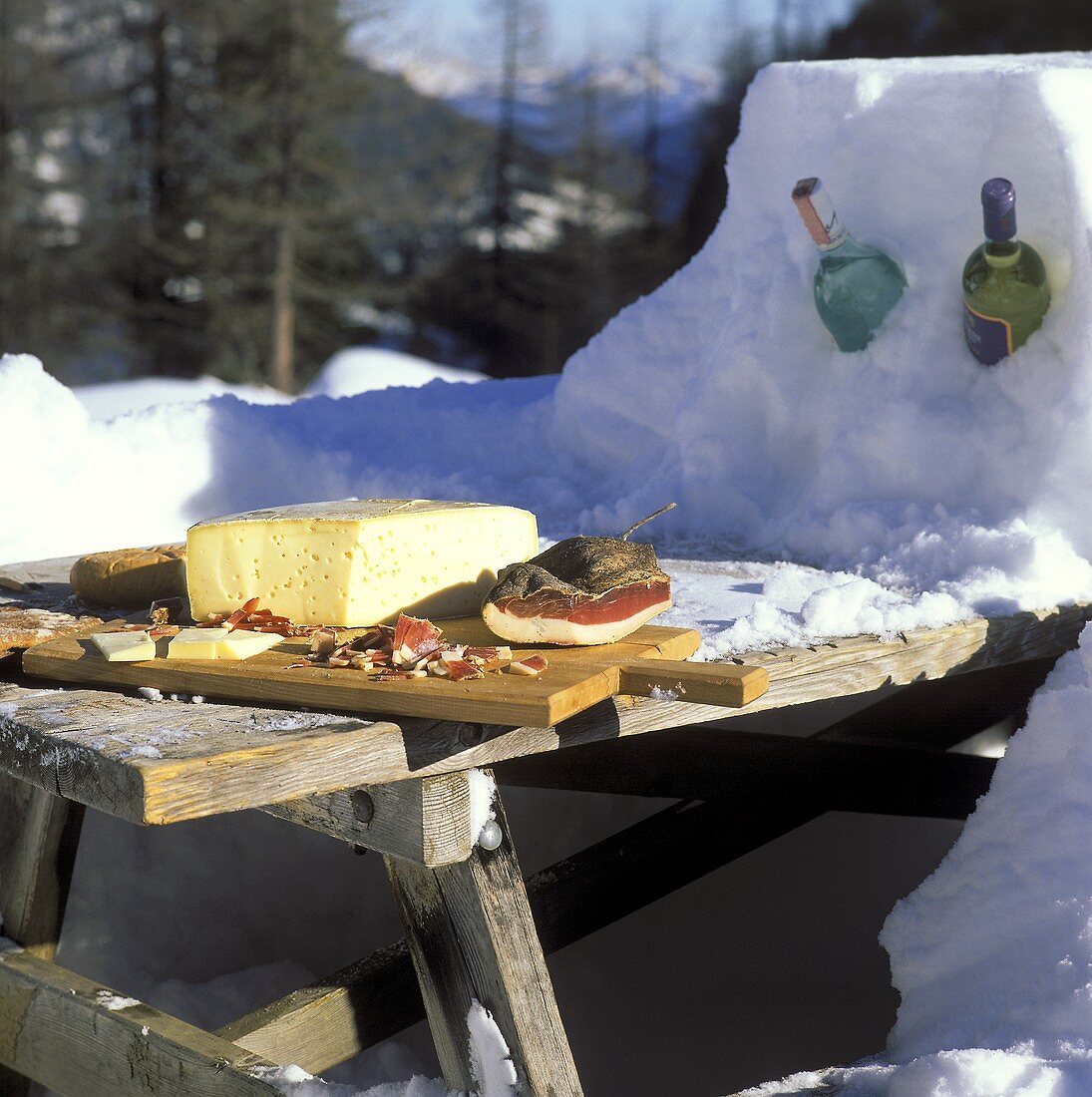 Brotzeit mit Speck,Käse auf Holztisch in Winterlandschaft