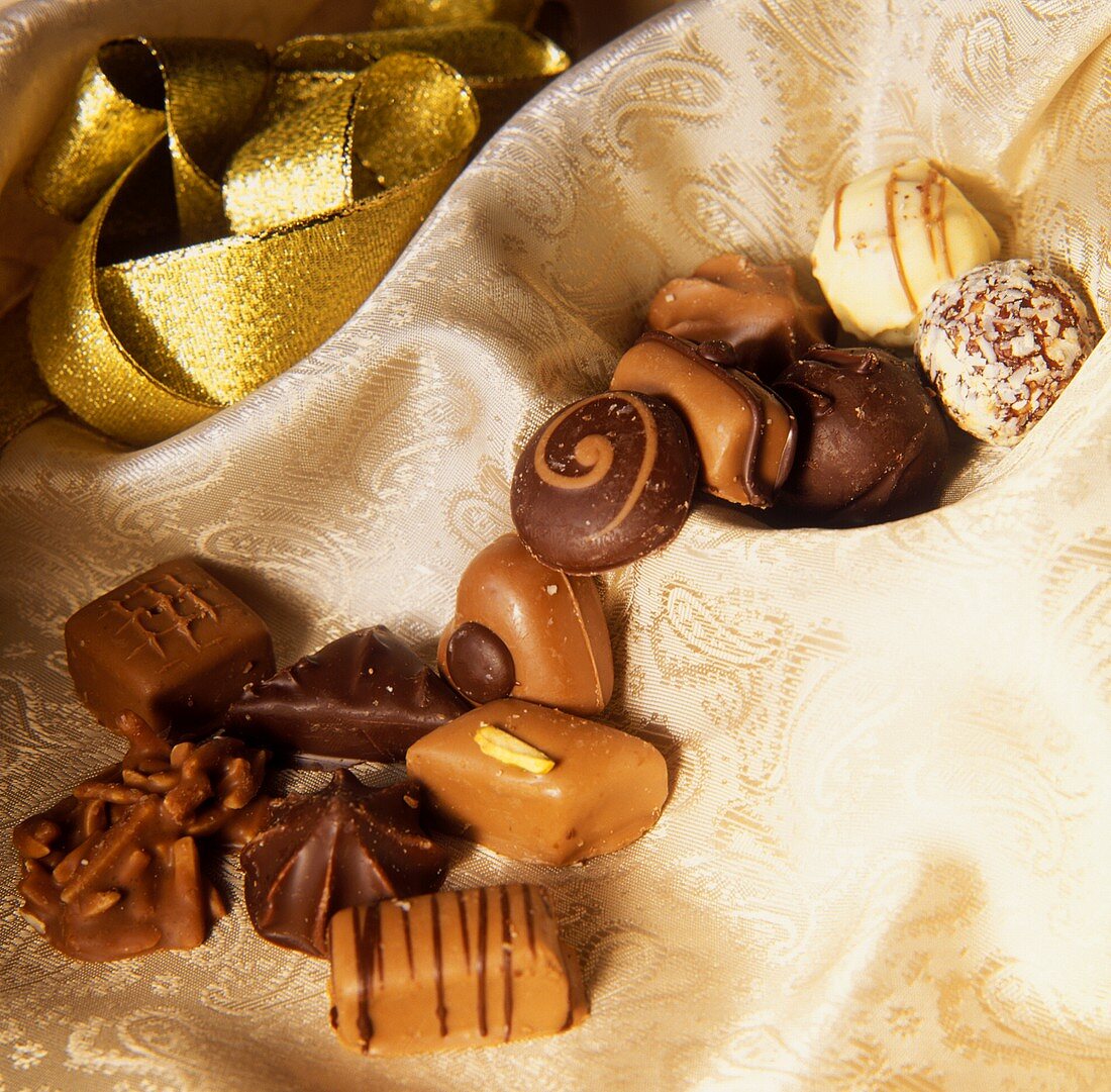 Various chocolates, fine fabric, gold ribbon behind