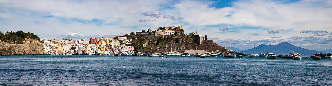 Panoramic view of town, colourful houses, sea and castle, Corricella, Procida island, Phlegraean Islands, Bay of Naples, Campania, Italy