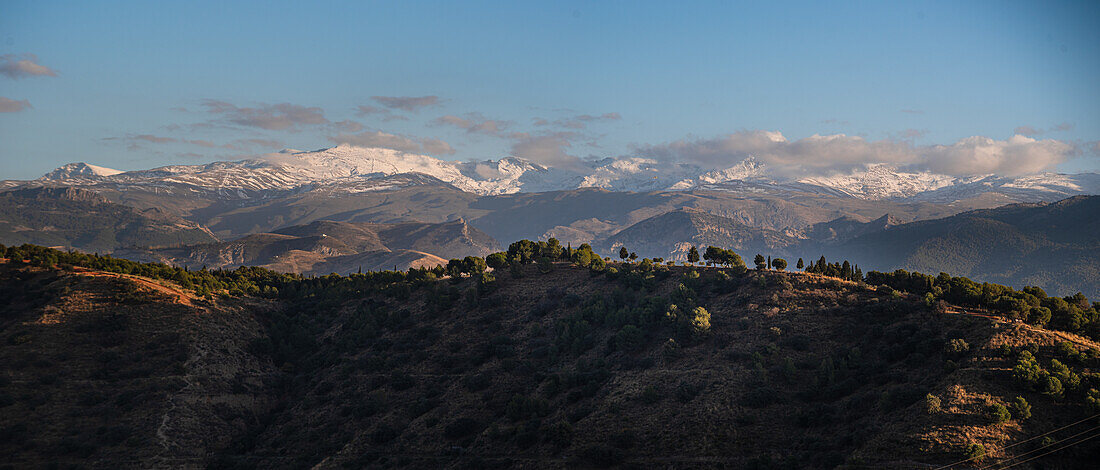 Sunset over hilly landscape in front of the Snowy Sierra Nevada, Albaicin, Granada, Andalucia, Spain