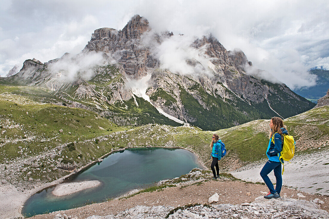 Wanderer auf einem Weg mit Blick auf den Lago dei Piani inferiore, Naturpark Drei Zinnen, Dolomiten, Südtirol, Italien