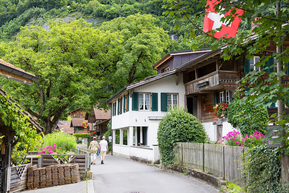 Ehepaar geht an traditionellen Chalets vorbei, Iseltwald, Schweiz