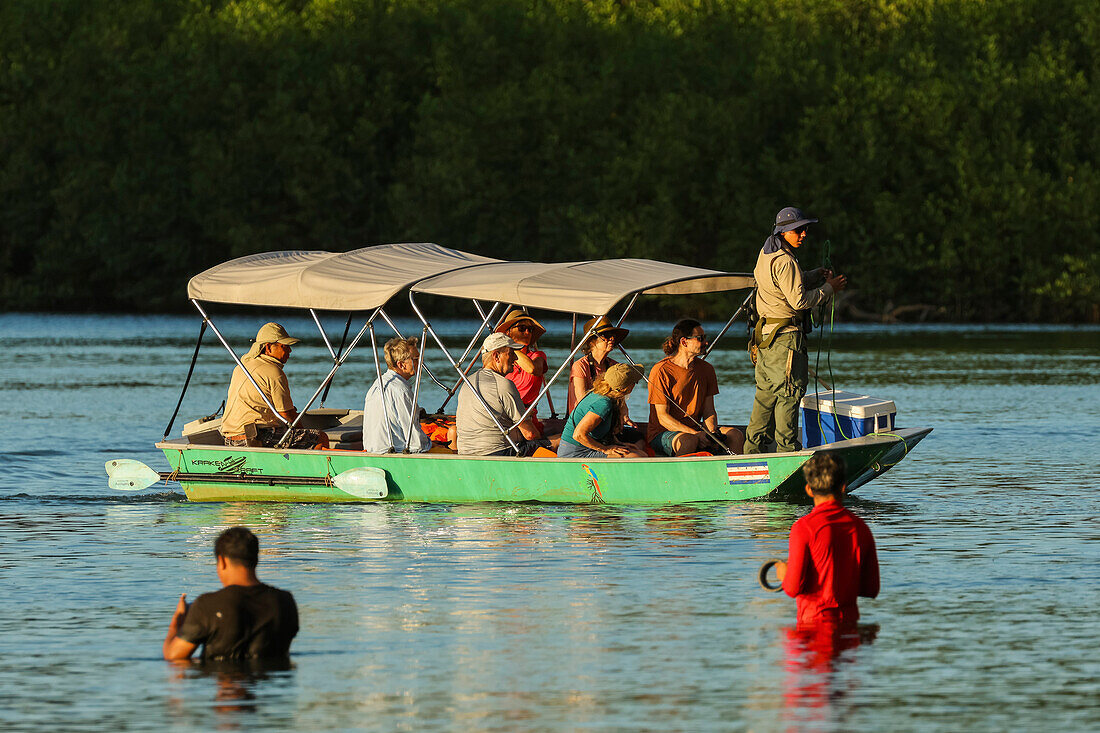 Tourists on boat trip through the mangrove fringed Nosara River estuary, with locals handline fishing, Boca Nosara, Nosara, Guanacaste, Costa Rica