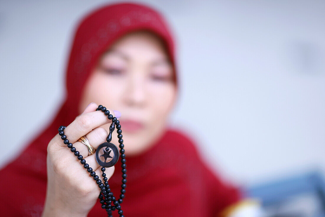 Muslimische Frau betet mit islamischen Perlen in der Hand, religiöse Meditation, Anbetung, Ramadan Konzept, Surabaya, Indonesien