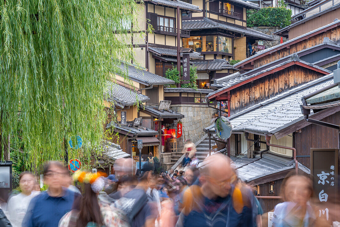 Blick auf eine belebte Straße und traditionelle Holzhäuser in Gion, Kyotoer Geisha-Viertel, Kyoto, Honshu, Japan