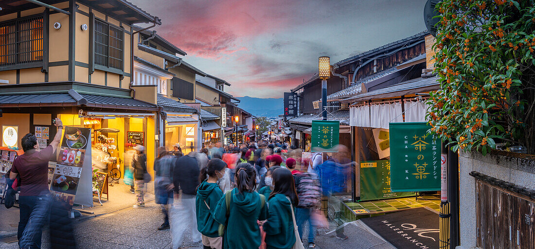 Blick auf eine belebte Straße mit traditionellen Holzhäusern und Geschäften in Gion, Kyotoer Geisha-Viertel, Kyoto, Honshu, Japan