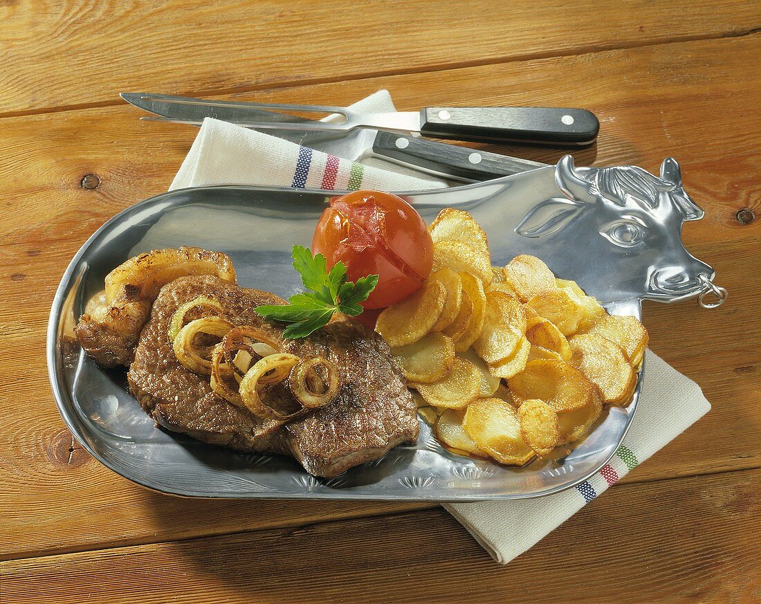 Rump steak with onions, fried potatoes & tomatoes on plate