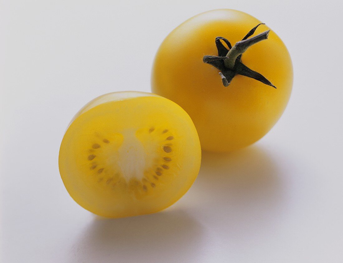 Gelbe Tomate und Tomatenhälfte