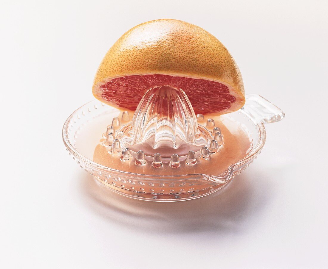 Pink grapefruit half on lemon squeezer with grapefruit juice