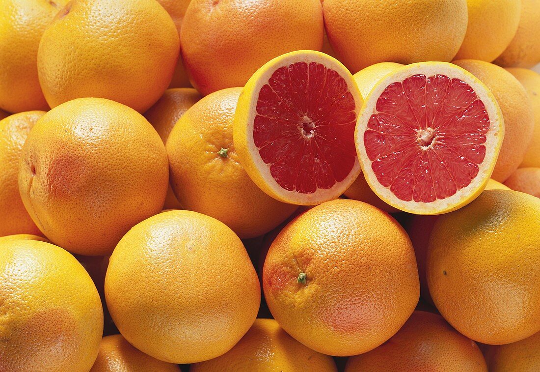 Pink grapefruits with two grapefruit halves (close-up)