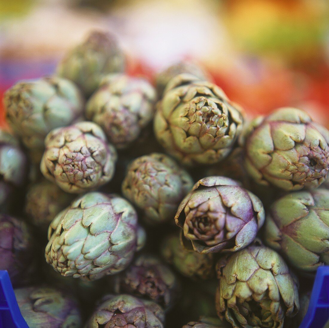 Lots of artichokes, in a pile, in a container