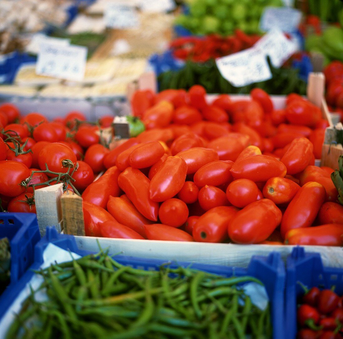 Tomaten zwischen anderem Gemüse in Steigen auf dem Markt