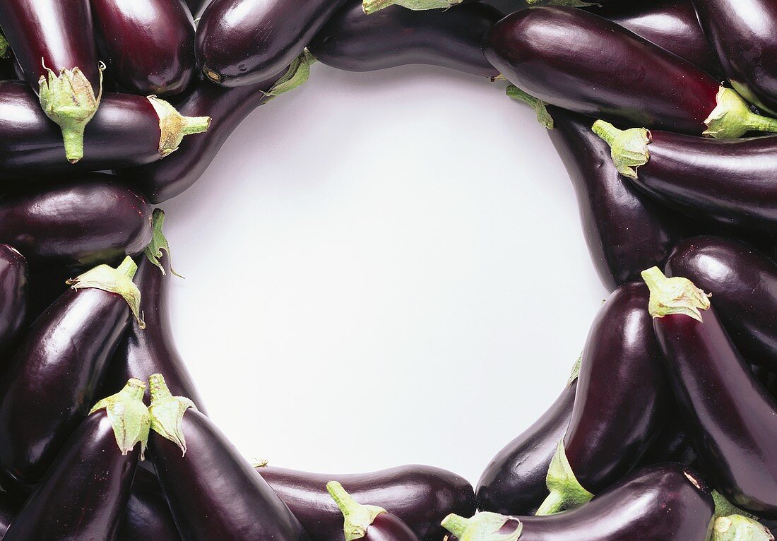 Purple aubergines laid around the edge of the picture