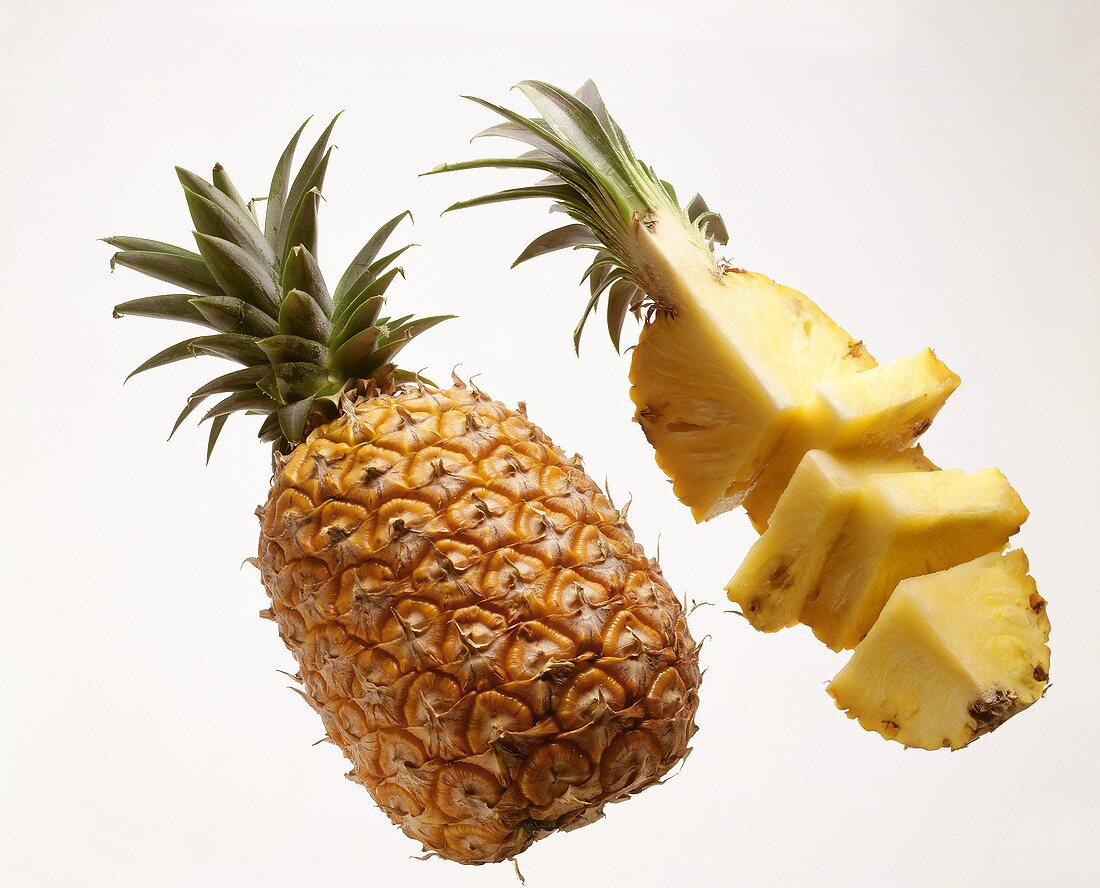 Whole pineapple and a pineapple quarter, a slice cut