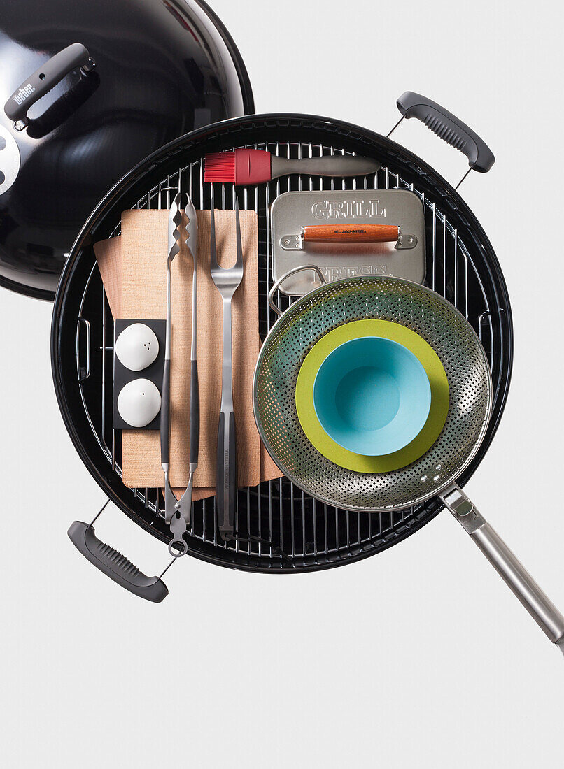 High angle view of barbecue grill and grilling utensils on white background