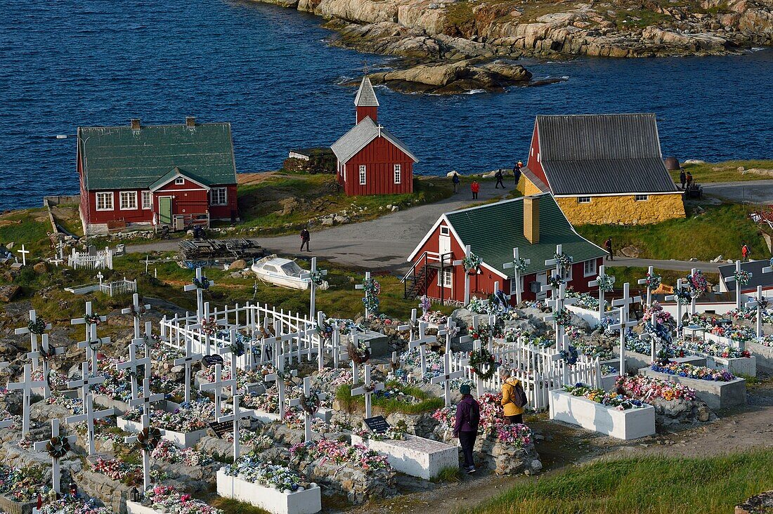 Grönland, Westküste, Baffin Bay, Upernavik, der Friedhof, die Särge werden auf die Oberfläche gestellt und dann mit Steinen oder Zement abgedeckt, der Boden kann nicht umgegraben werden, die Gräber werden dann mit künstlichen Blumen geschmückt, die alte Kirche und die Museumsgebäude im Hintergrund