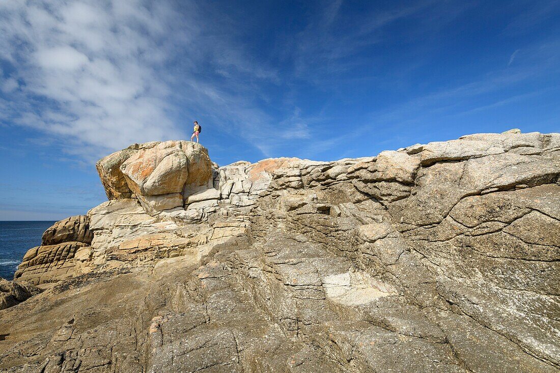 France, Finistere, Penmarch, hiker on the rocks of Saint-Guenolé