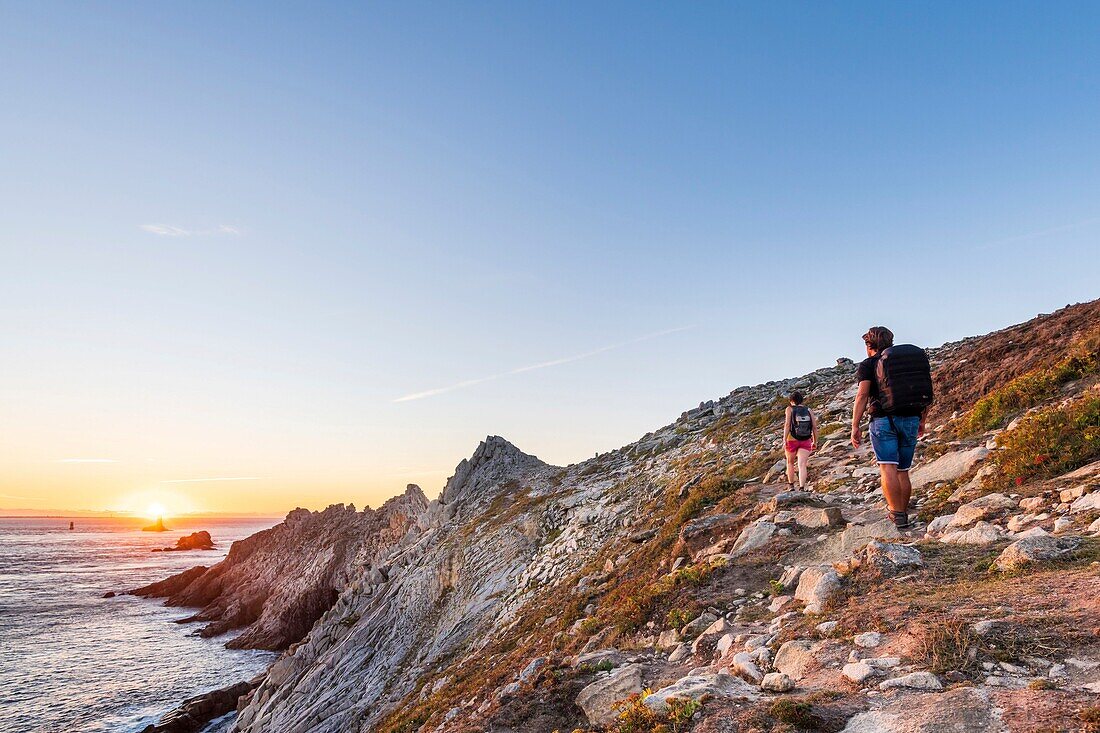 Frankreich, Finistere, Plogoff, Wanderer bei Sonnenuntergang an der Pointe du Raz