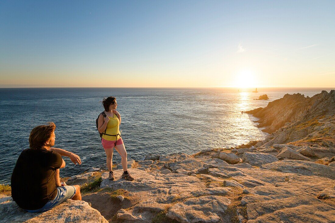 Frankreich, Finistere, Plogoff, Wanderer bei Sonnenuntergang an der Pointe du Raz