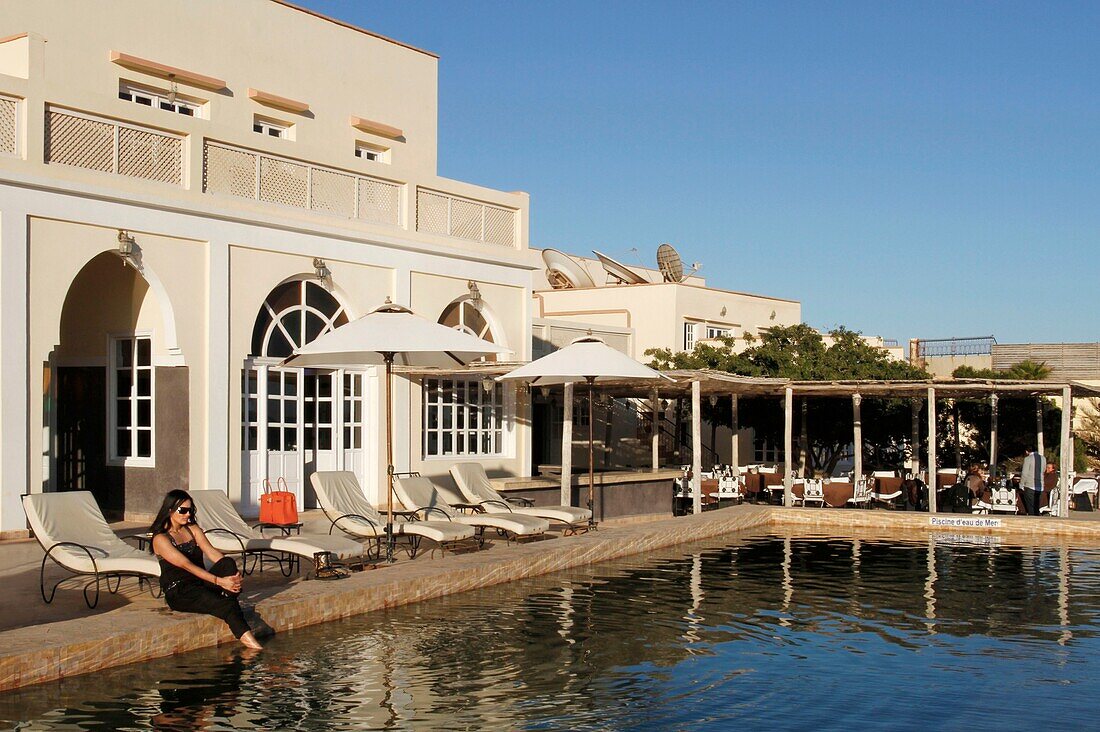 Morocco, Western Sahara, Dakhla, young Moroccan women on deckchairs in front of the swimming pool of Hotel Calipau