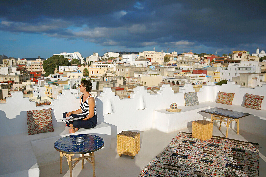 Marokko, Tanger Region Tetouan, Tanger, Dar Nour Hotel, Frau auf der Terrasse des Gästehauses Dar Nour mit Blick auf die Kasbah, bei Einbruch der Dunkelheit