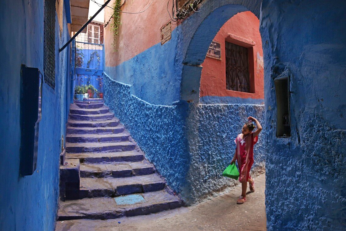 Marokko, Tanger Region Tetouan, Tanger, marokkanisches Mädchen in einer Gasse der Medina mit blauen Wänden