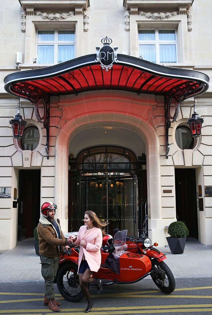 France, Paris, Royal Monceau hotel, woman riding in a retro side car in front of the hotel facade guarded by two valet