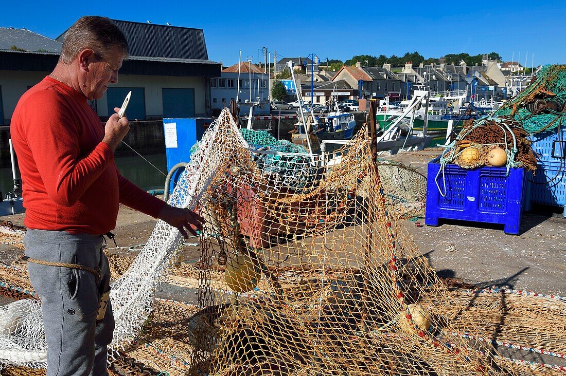 France, Calvados, Cote de Nacre, Port en Bessin, the fishing port, fisherman repairing fishing nets