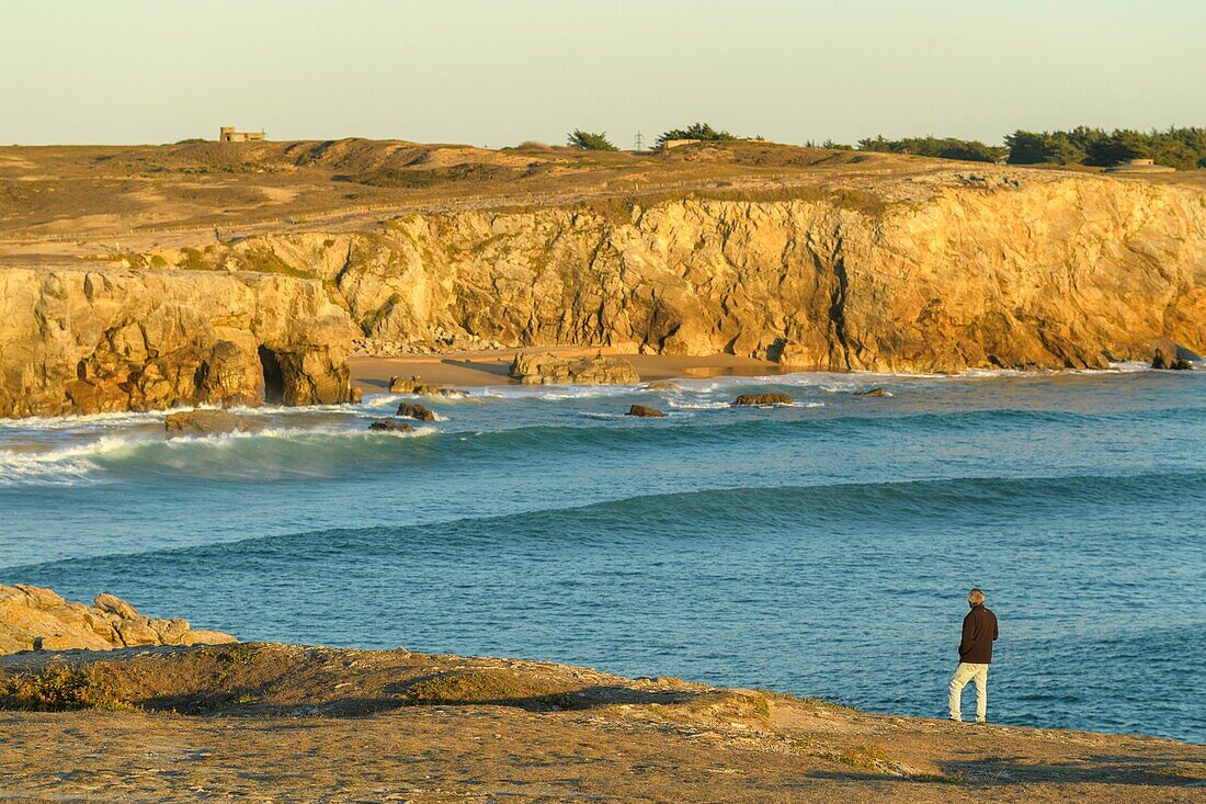 France, Morbihan, Saint-Pierre-Quiberon, man in front of the wild coast and the cliffs of Porz at sunset