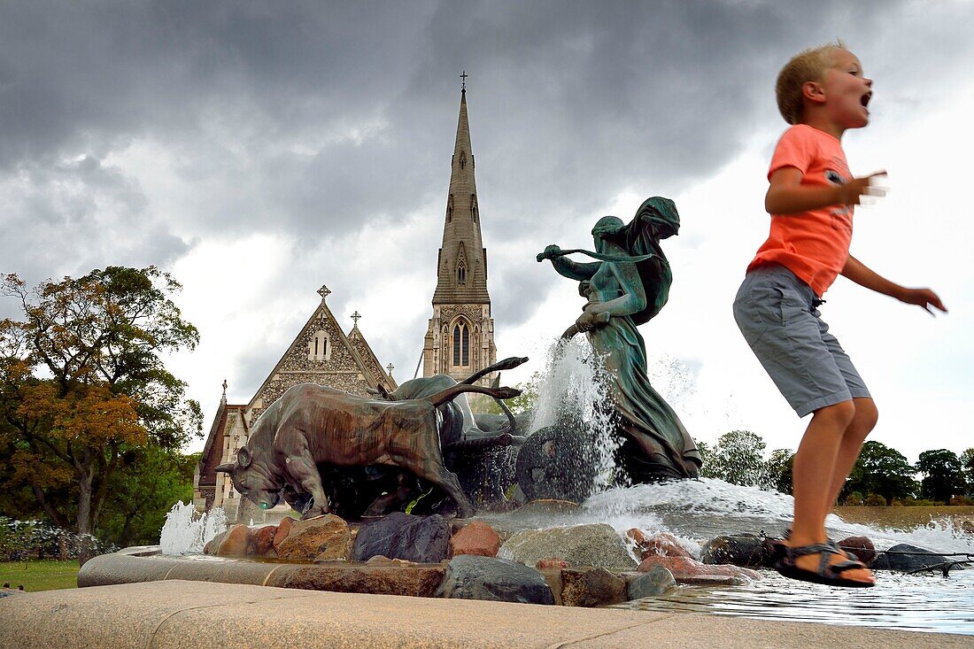 Dänemark, Seeland, Kopenhagen, der Gefionsbrunnen (Gefionspringvandet), der eine Gruppe von Tieren darstellt, die von der Göttin Gefjon angeführt werden, im Hintergrund die Kirche Saint-Alban