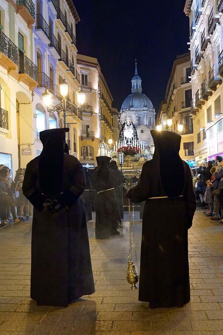 Spain, Aragon Region, Zaragoza Province, Zaragoza, Religious float being carried through the streets during Semana Santa, (Holy Week) celebrations, Basilica de Nuestra Senora de Pilar in the background