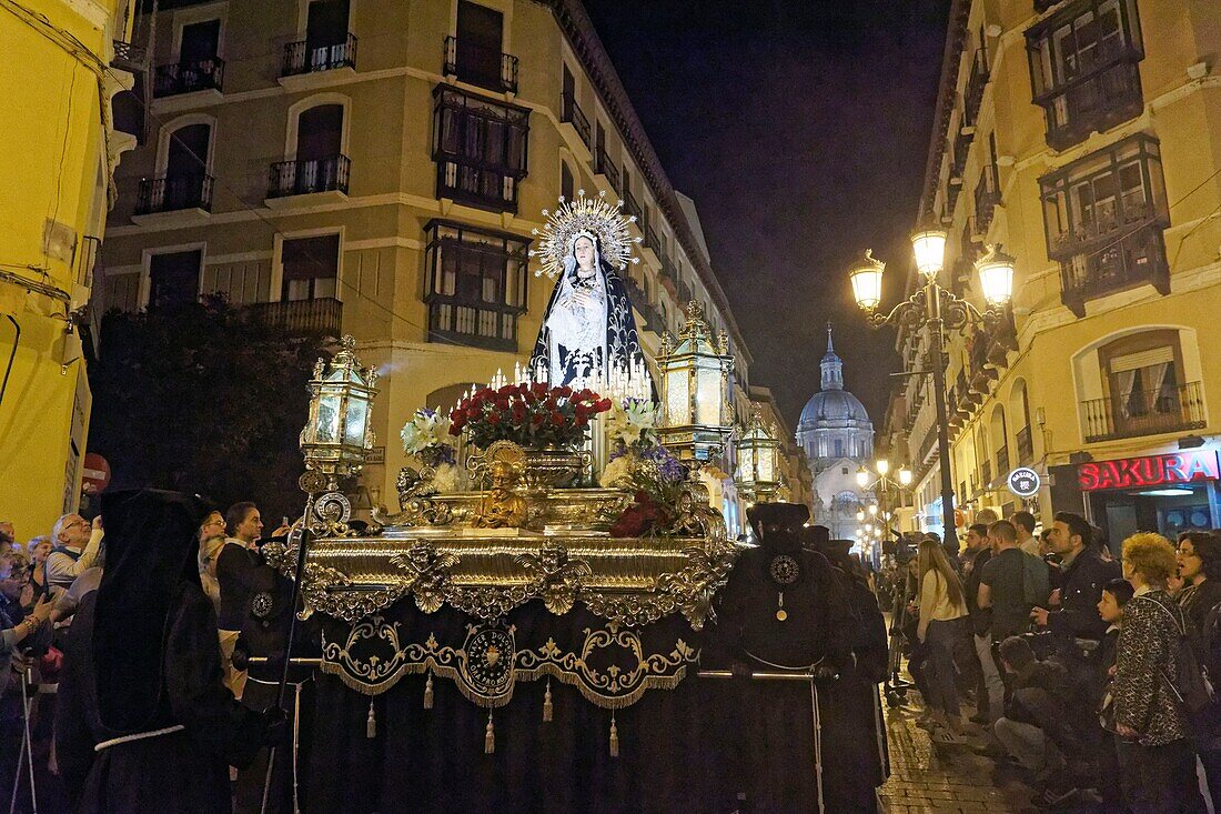 Spain, Aragon Region, Zaragoza Province, Zaragoza, Religious float being carried through the streets during Semana Santa, (Holy Week) celebrations, Basilica de Nuestra Senora de Pilar in the background