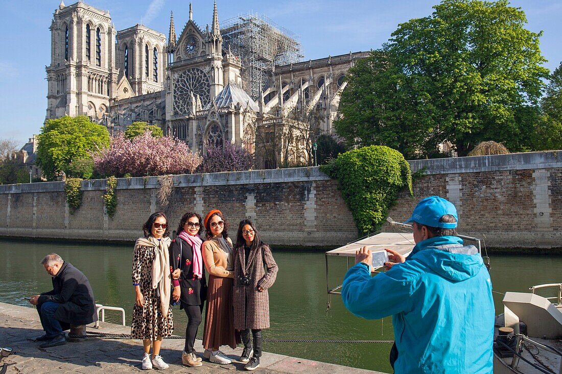 France, Paris, Notre Dame de Paris Cathedral, two days after the fire, April 17, 2019, Asian tourists being photographed in front of the cathedral from the quay of Montebello