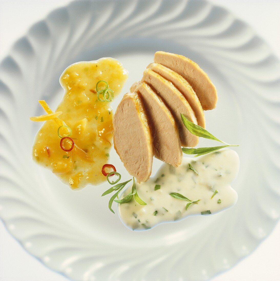 Slices of chicken breast with mango & tarragon sauce on plate