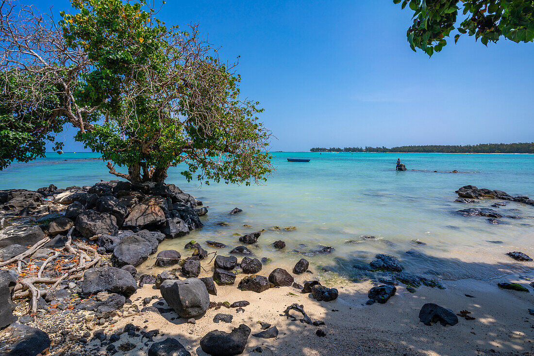 Blick auf einen Mann beim Fischen am Mont Choisy Beach und den türkisfarbenen Indischen Ozean an einem sonnigen Tag, Mauritius, Indischer Ozean, Afrika