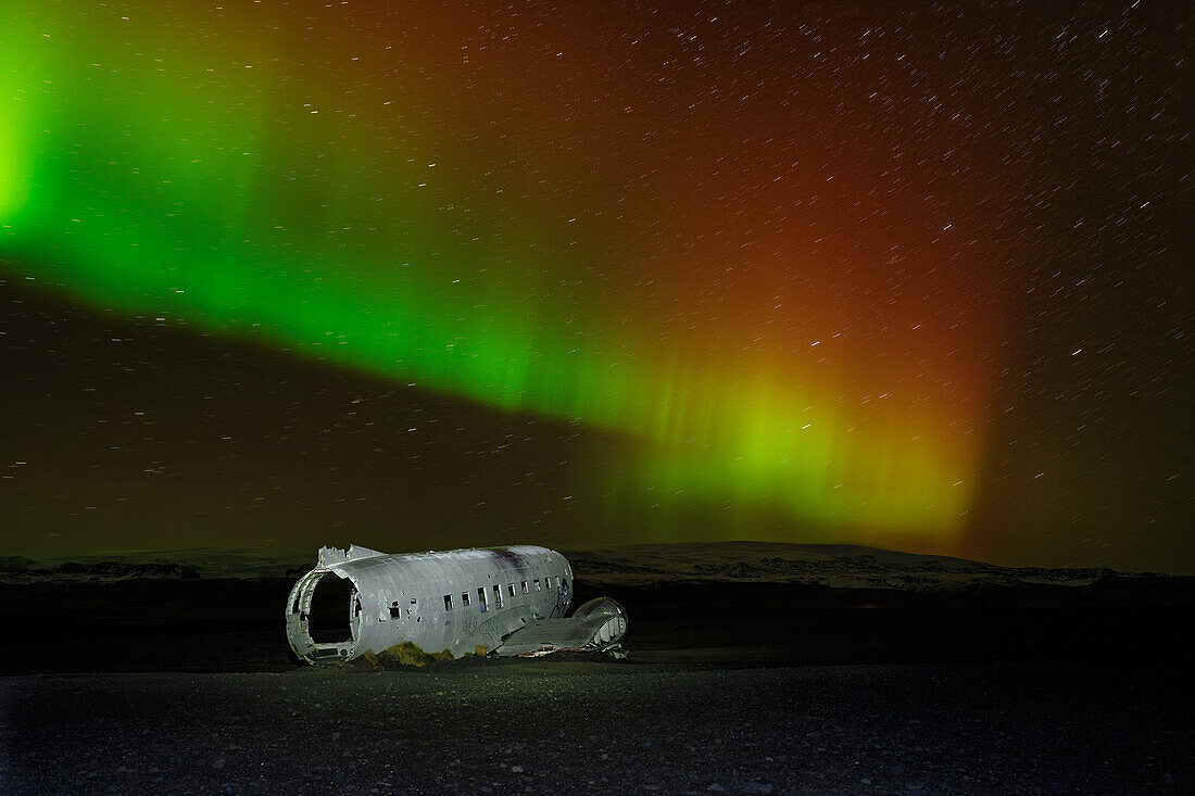 Ein abgestürztes DC-3-Flugzeug unter den Polarlichtern (Aurora Borealis), Island, Polargebiete
