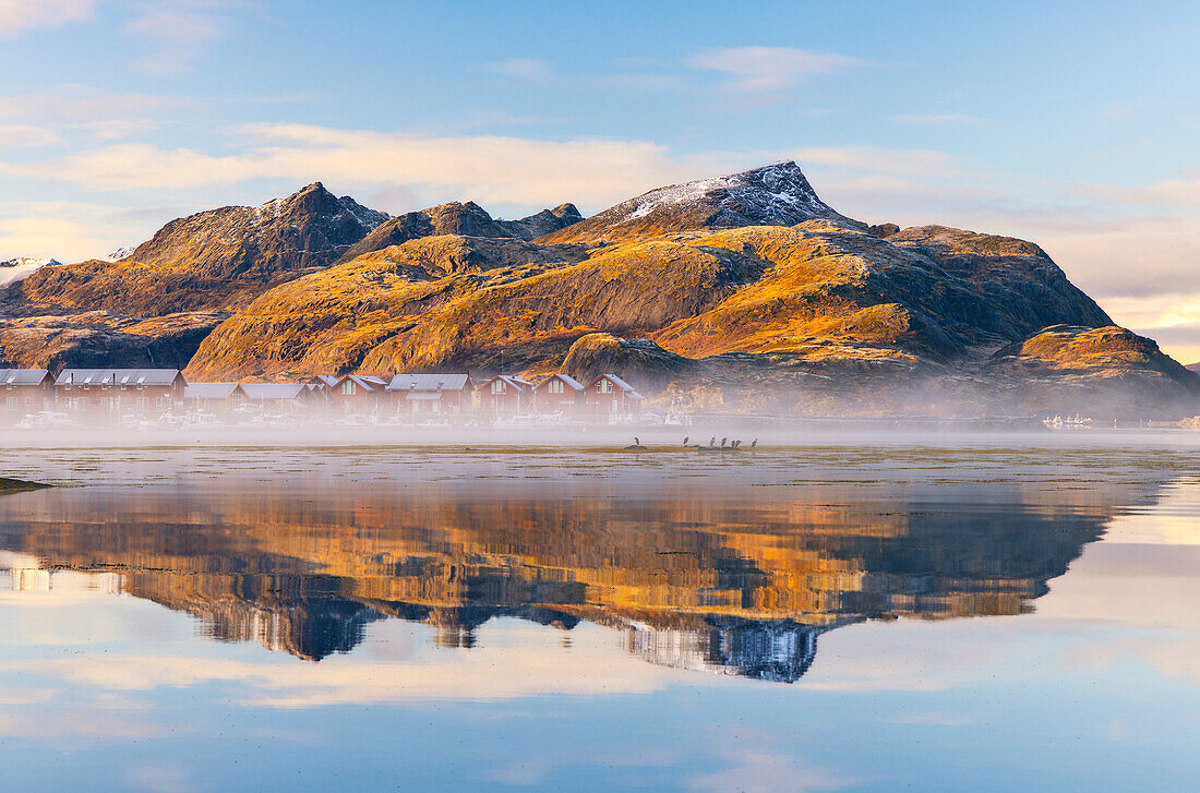 Mountains and rorbuer reflected in a Fjord during sunset, Leknes, Vestvagoy, Nordland, Lofoten Islands, Norway, Scandinavia, Europe