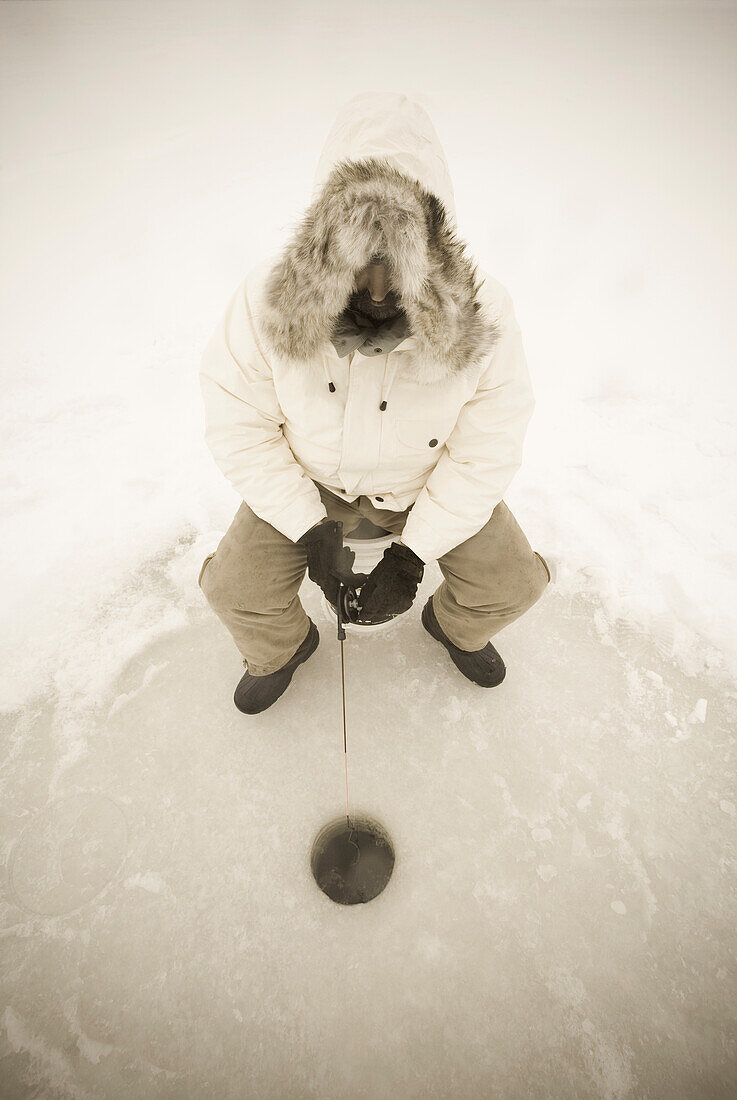 USA, NY, Hammond, Blick von oben auf einen Mann beim Eisfischen auf dem zugefrorenen Black Lake