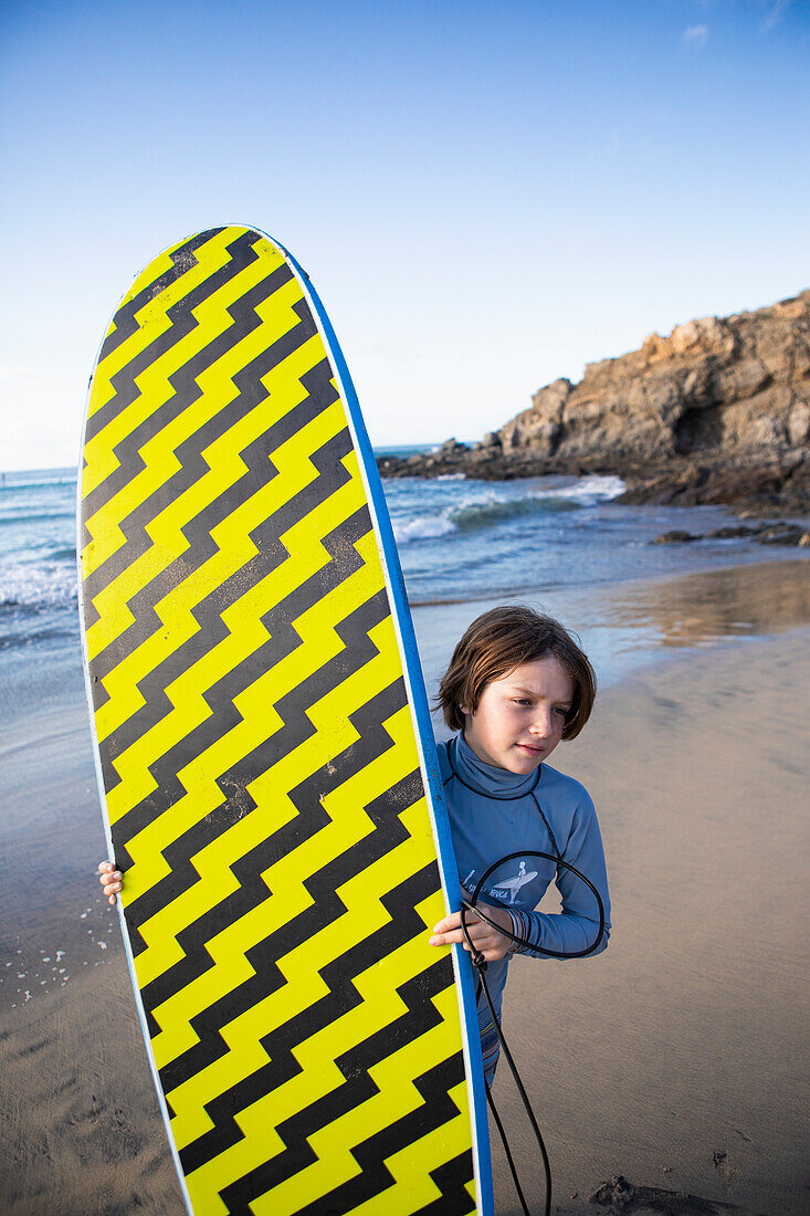 Mexiko, Baja, Pescadero, Junge mit Surfbrett am Strand