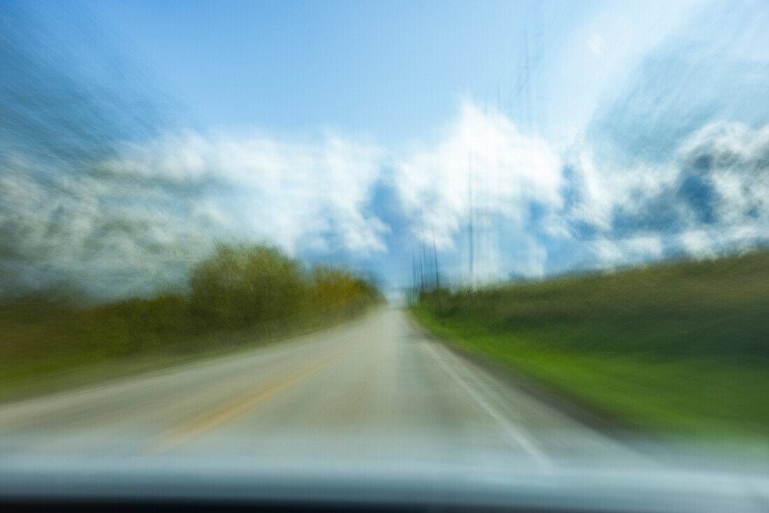 USA, Wisconsin, Landstraße und Wolken aus dem fahrenden Auto gesehen