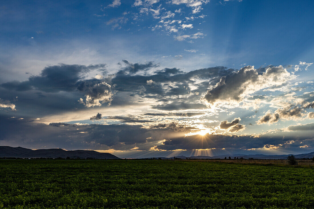 Bewölkter Himmel bei Sonnenuntergang über einer ländlichen Landschaft