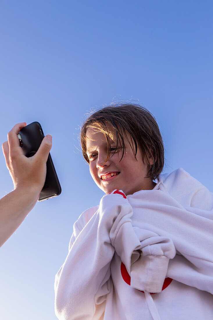 Boy (10-11) smiling while looking at smart phone